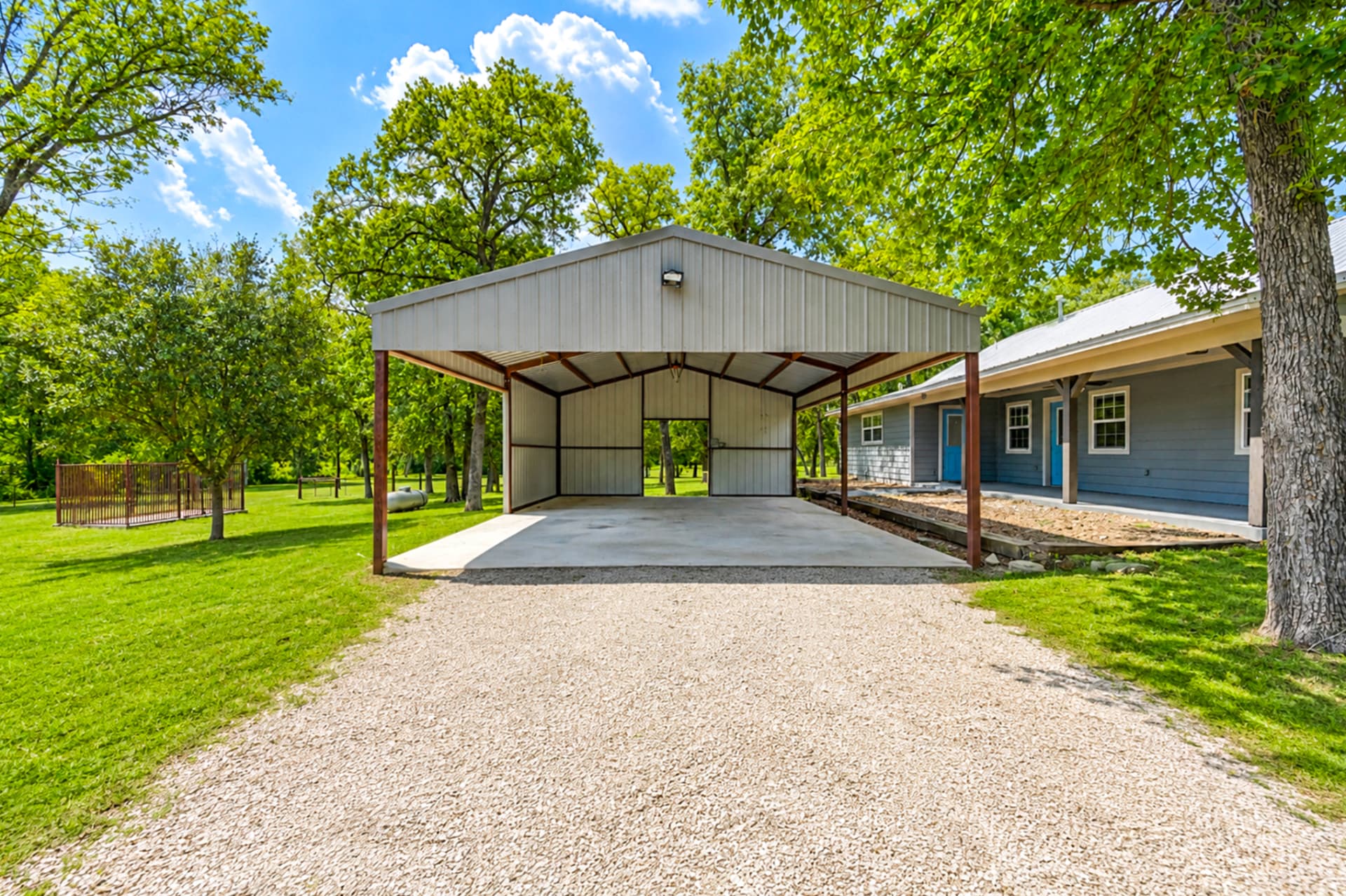 Vaulted 22' x 30' carport with concrete slab and gravel drive beside the farmhouse