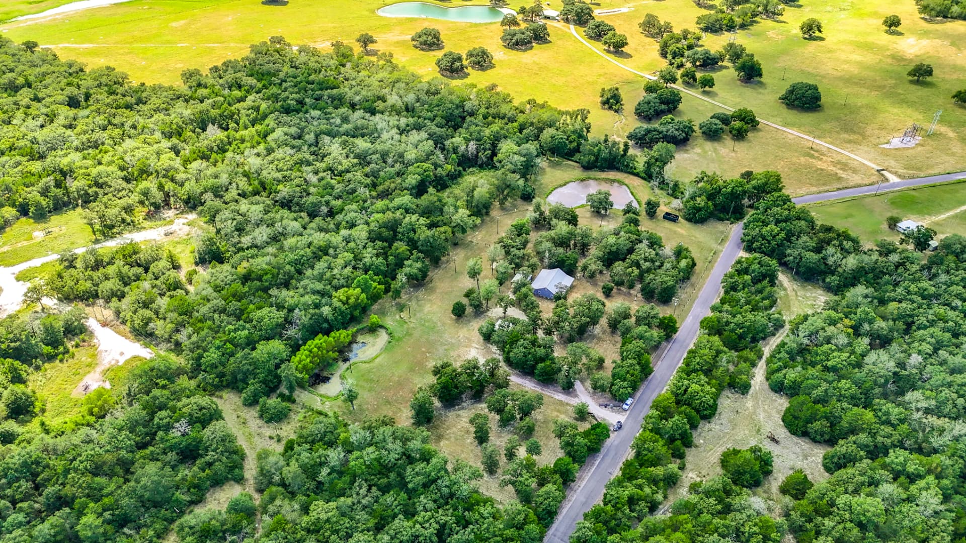 Aerial view of the property's ponds, oaks, and pasture with country road frontage
