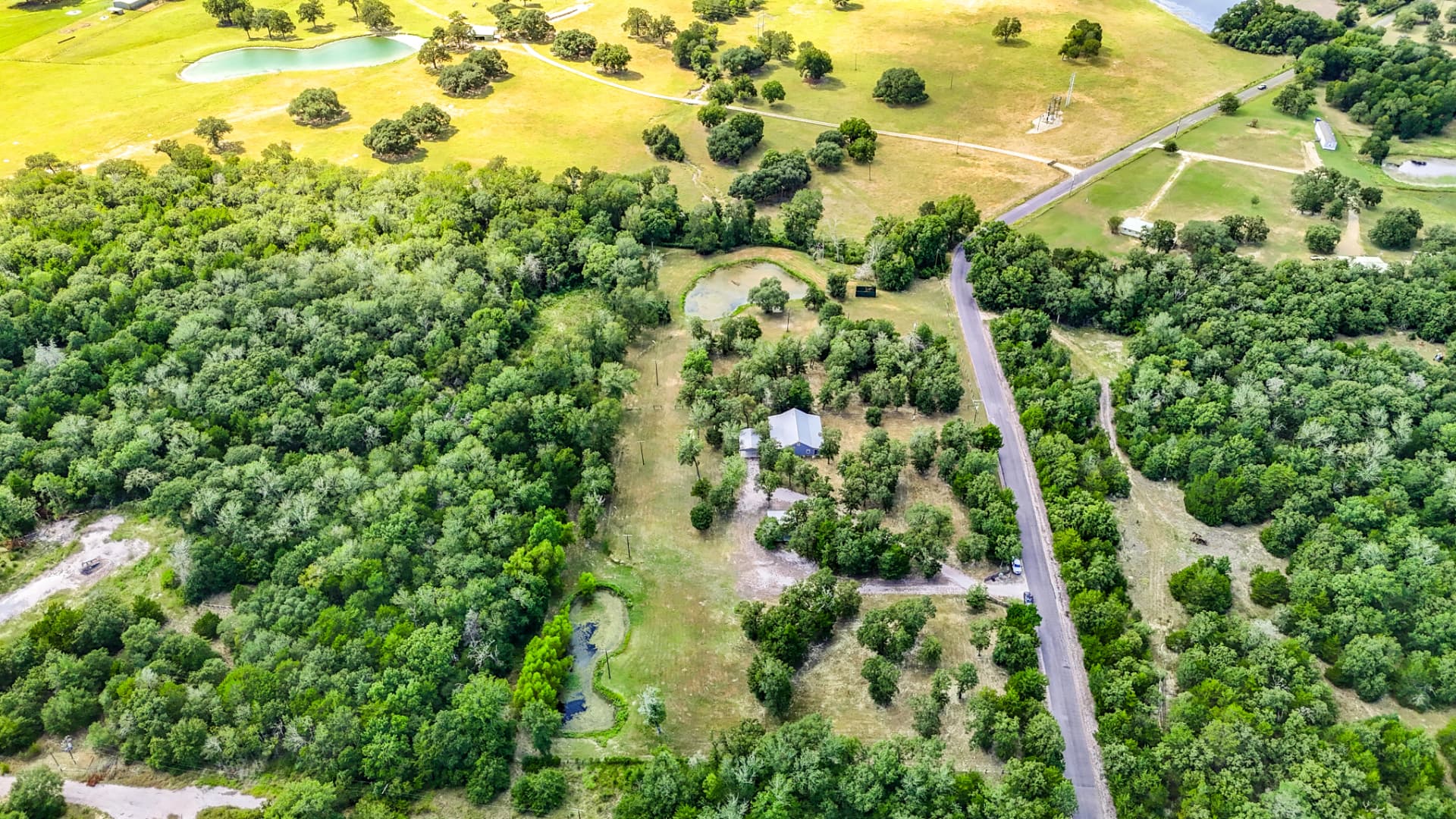 Aerial view showing the property, county road frontage, and surrounding pastures